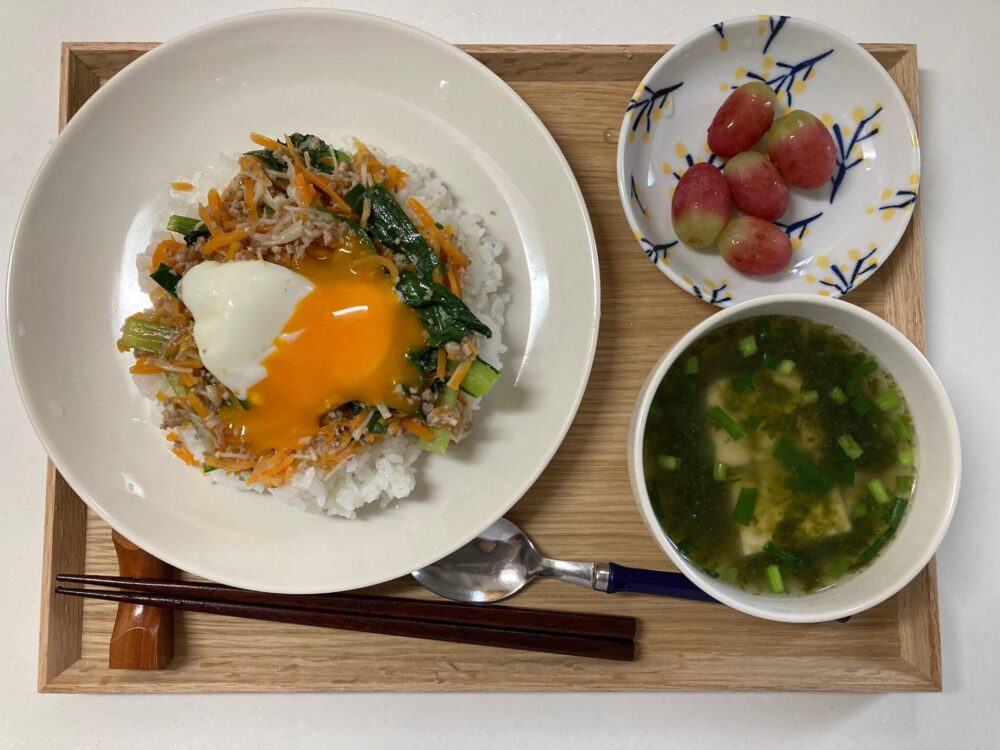 ジューシーそぼろと野菜のビビンバとスープ、ぶどうをお盆にのせたオイシックスのミールキットメニュー